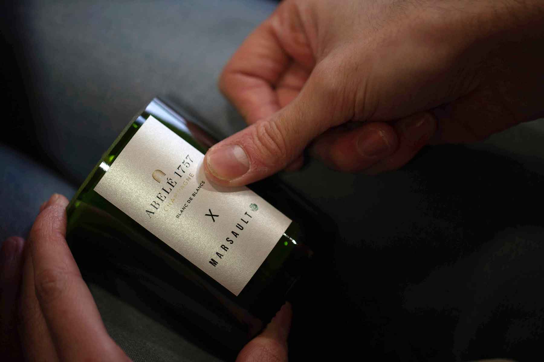 Putting label on Blanc de Blancs Abelé 1757 candle by Marsault